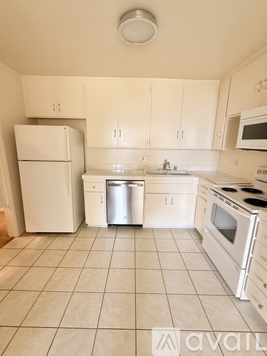 A kitchen with white appliances and cabinets.