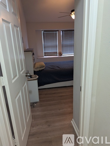 A bedroom with a bed, a window with blinds, and a white door.