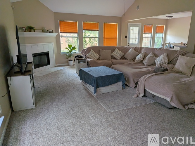 A living room with a grey couch, a blue ottoman, and a television.