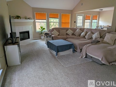 A living room with a grey couch, a blue ottoman, and a television.