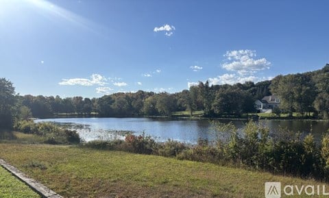 A sunny day at the lake with a house in the distance.