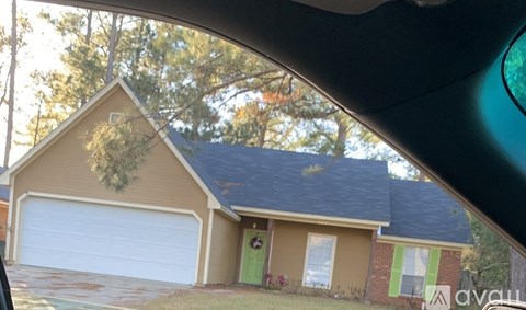 A house with a garage door is visible from a car window.