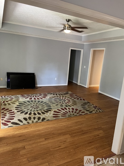A room with a ceiling fan and a rug on the floor.
