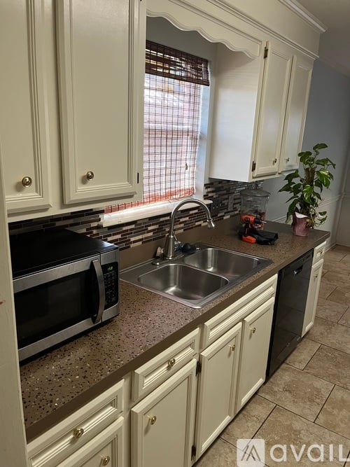 A kitchen with white cabinets and a black microwave.