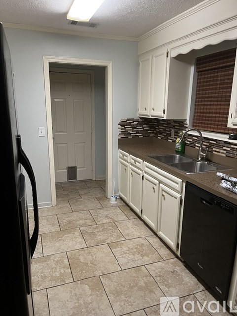 A kitchen with a black fridge and a black dishwasher.