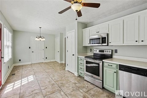 A kitchen with a fan and a microwave on the counter.