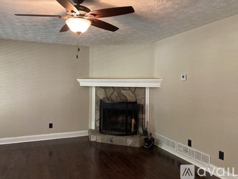 A living room with a fireplace and a ceiling fan.