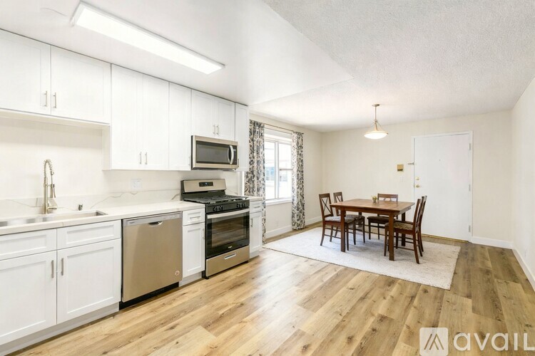 A kitchen with white cabinets and a wooden floor.