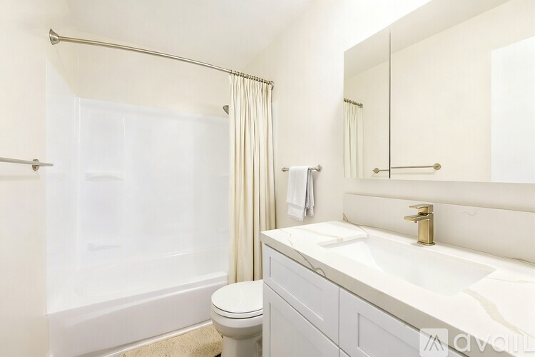 A white bathroom with a toilet, sink, and shower.