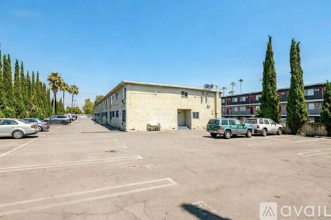 A parking lot with a building and cars parked in front.