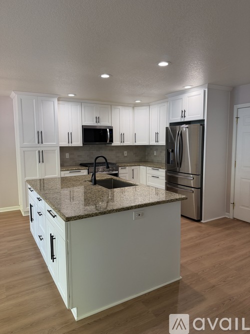 A kitchen with white cabinets and a granite countertop.
