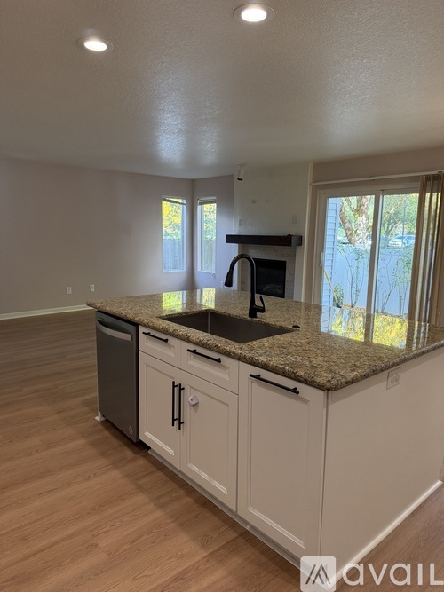 A kitchen with a granite countertop and wooden flooring.