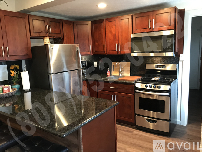 A kitchen with wooden cabinets and a stainless steel refrigerator.