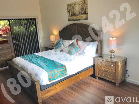 A bedroom with a large bed and a wooden nightstand.