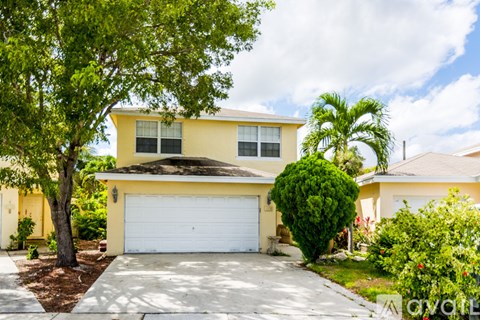 A yellow house with a white garage door is for sale.
