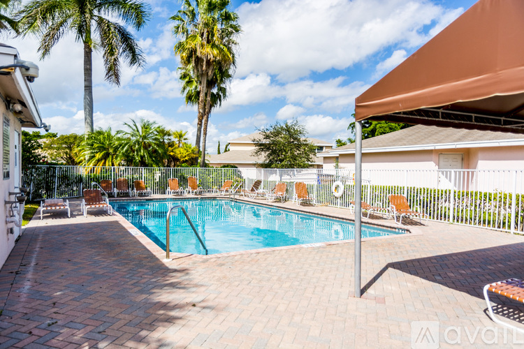 A pool surrounded by palm trees and a patio area.