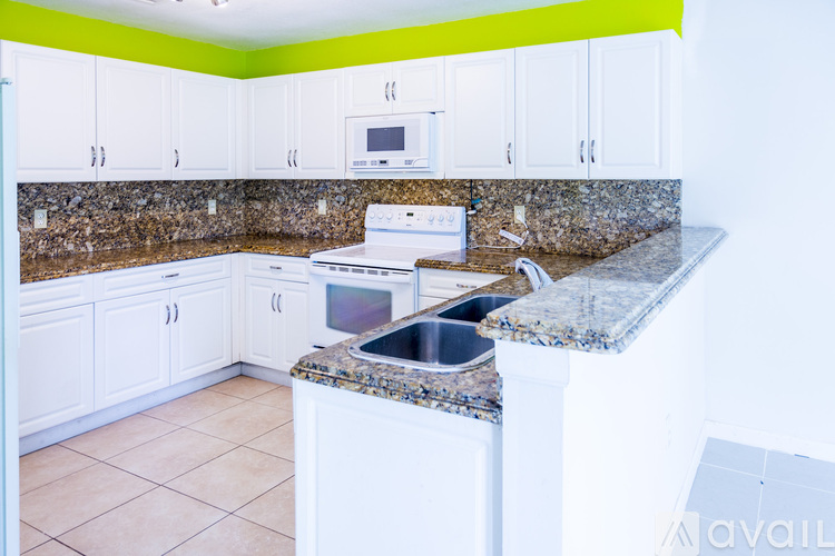 A kitchen with a granite counter top and white cabinets.