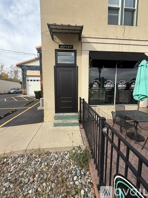 A black door with a glass window is on a tan building.