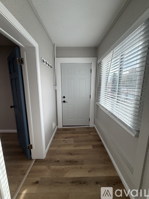 A hallway with a white door and a window with blinds.