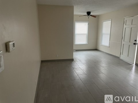 A spacious room with tile flooring and a ceiling fan.