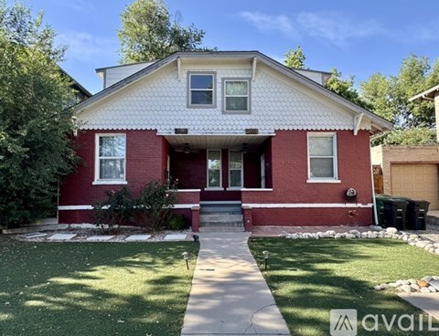 A red brick house with a white roof and a green lawn in front.
