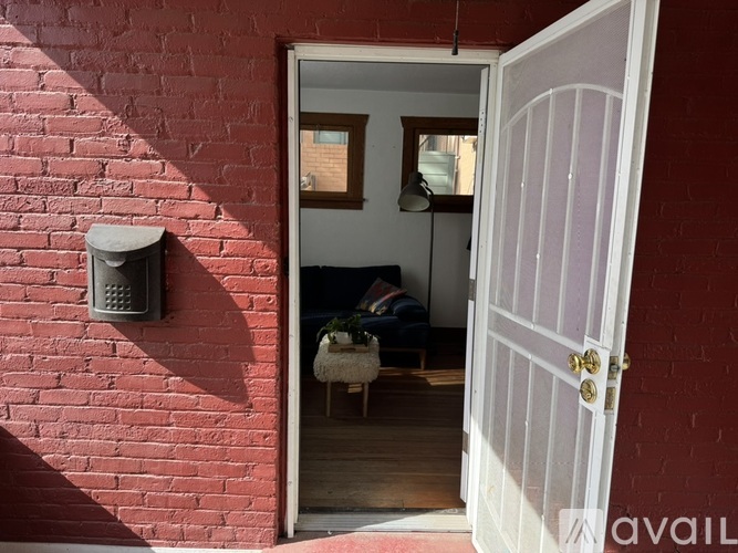 A white door is open to a room with a brick wall.