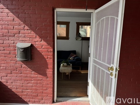 A white door is open to a room with a brick wall.
