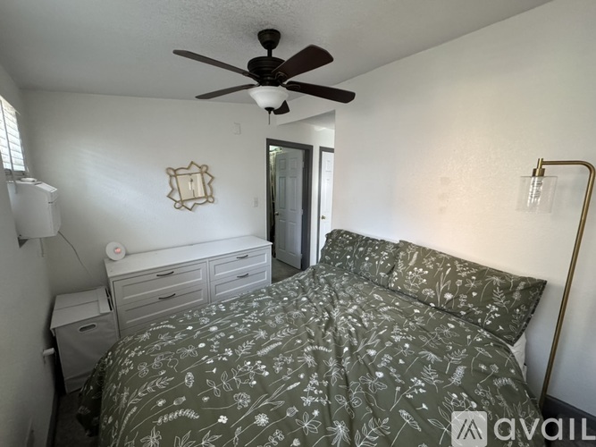 A bedroom with a bed, dresser, and ceiling fan.