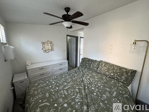 A bedroom with a bed, dresser, and ceiling fan.