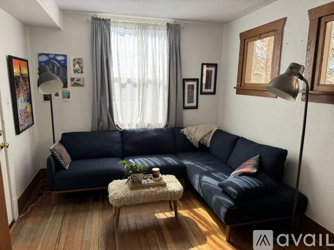 A living room with a dark blue couch and a white sheepskin rug.