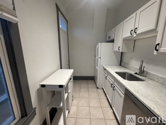 A kitchen with white cabinets and a white table.