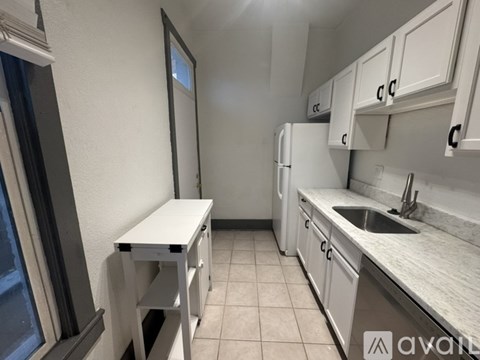 A kitchen with white cabinets and a white table.
