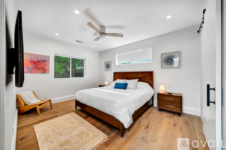 A bedroom with a large bed, a ceiling fan, and a rug on the floor.