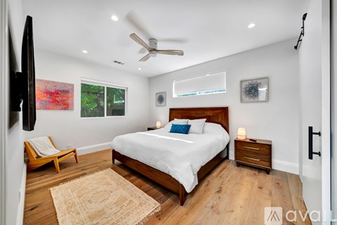A bedroom with a large bed, a ceiling fan, and a rug on the floor.