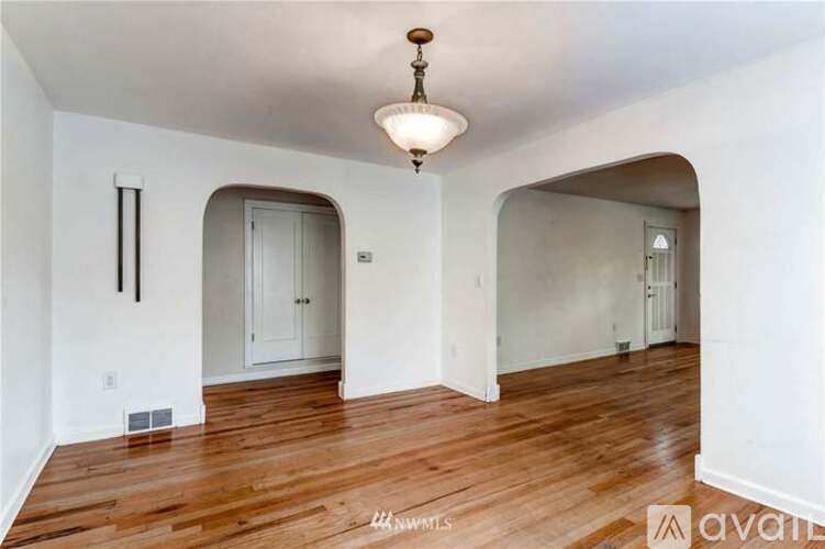 A room with wooden floors and white walls, with a chandelier hanging from the ceiling.