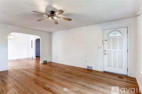 A room with a ceiling fan and wooden flooring.