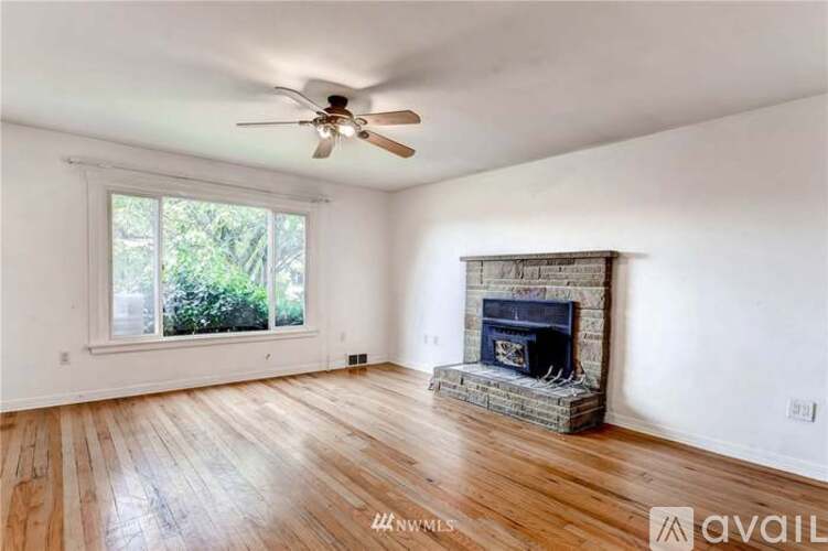 A living room with a fireplace and a ceiling fan.