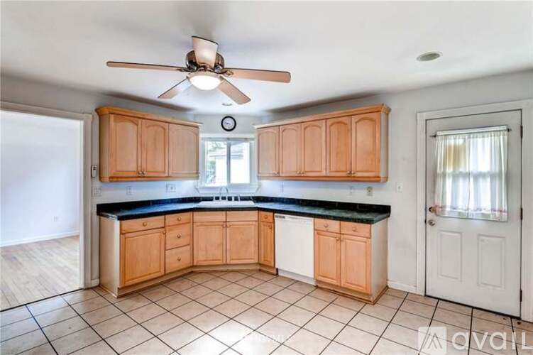A kitchen with wooden cabinets and a fan on the ceiling.
