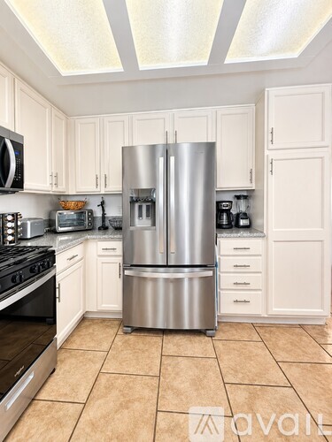 A kitchen with a stainless steel refrigerator and black stove.