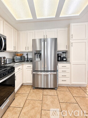 A kitchen with a stainless steel refrigerator and black stove.