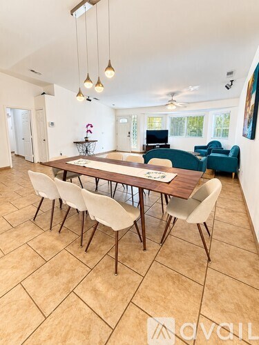 A dining room with a wooden table and white chairs.