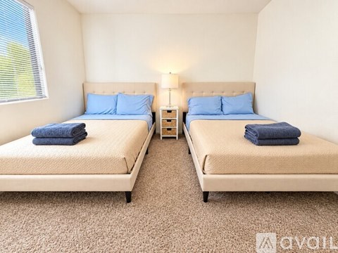 Two twin beds with blue pillows and towels in a room.