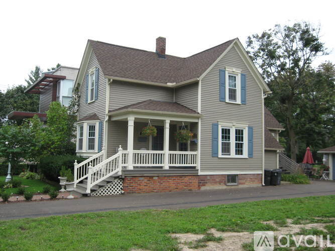 A two-story house with a porch and a brick foundation.