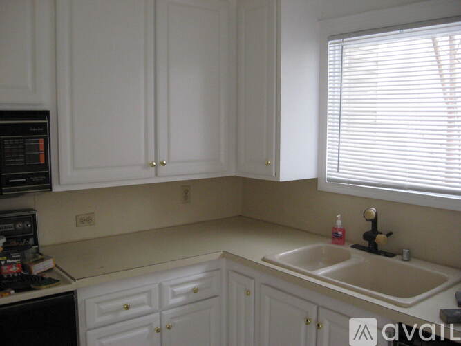 A kitchen with white cabinets and a black microwave.