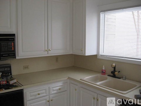 A kitchen with white cabinets and a black microwave.