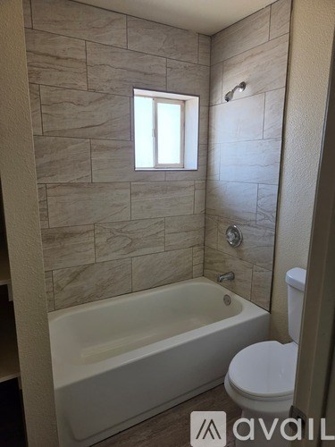 A bathroom with a tub, toilet and a window.