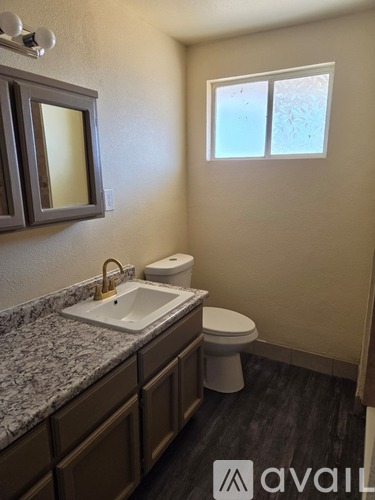 A bathroom with a sink, toilet, and window.