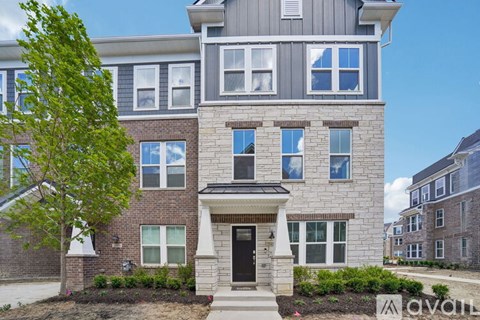 A two-story house with a front yard and a tree.