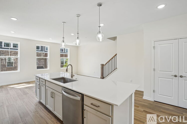 A modern kitchen with a stainless steel sink and white countertops.