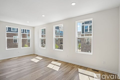 A spacious room with wooden floors and large windows overlooking a cityscape.